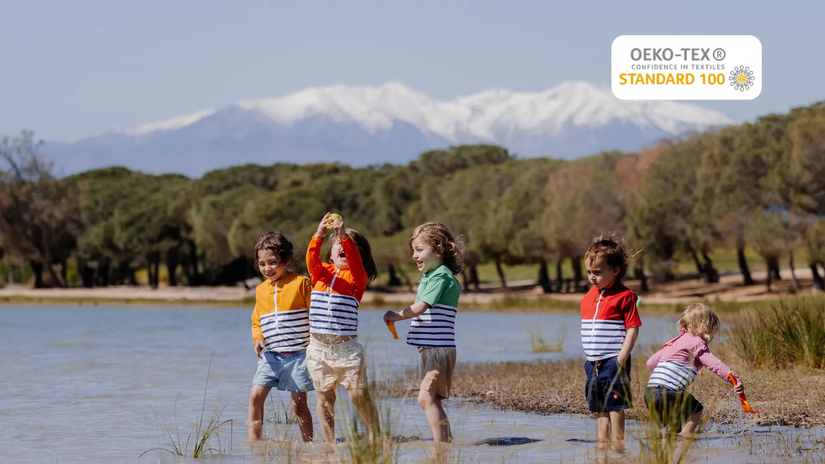 5 jeunes enfants jouant près de l'eau portant chacun un tee-shirt anti-noyade enfant de couleurs distinctes