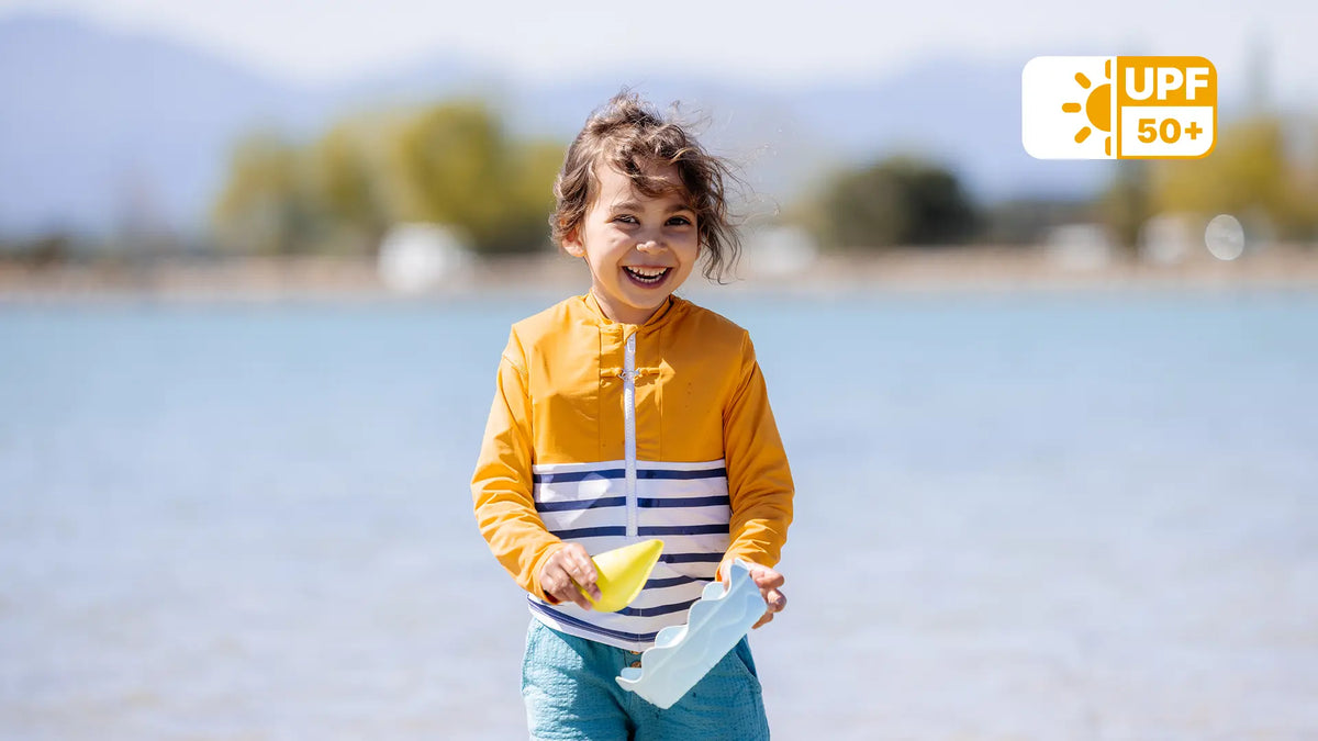 Jeune fille portant un tee-shirt anti-noyade enfant jaune et jouant près de l'eau