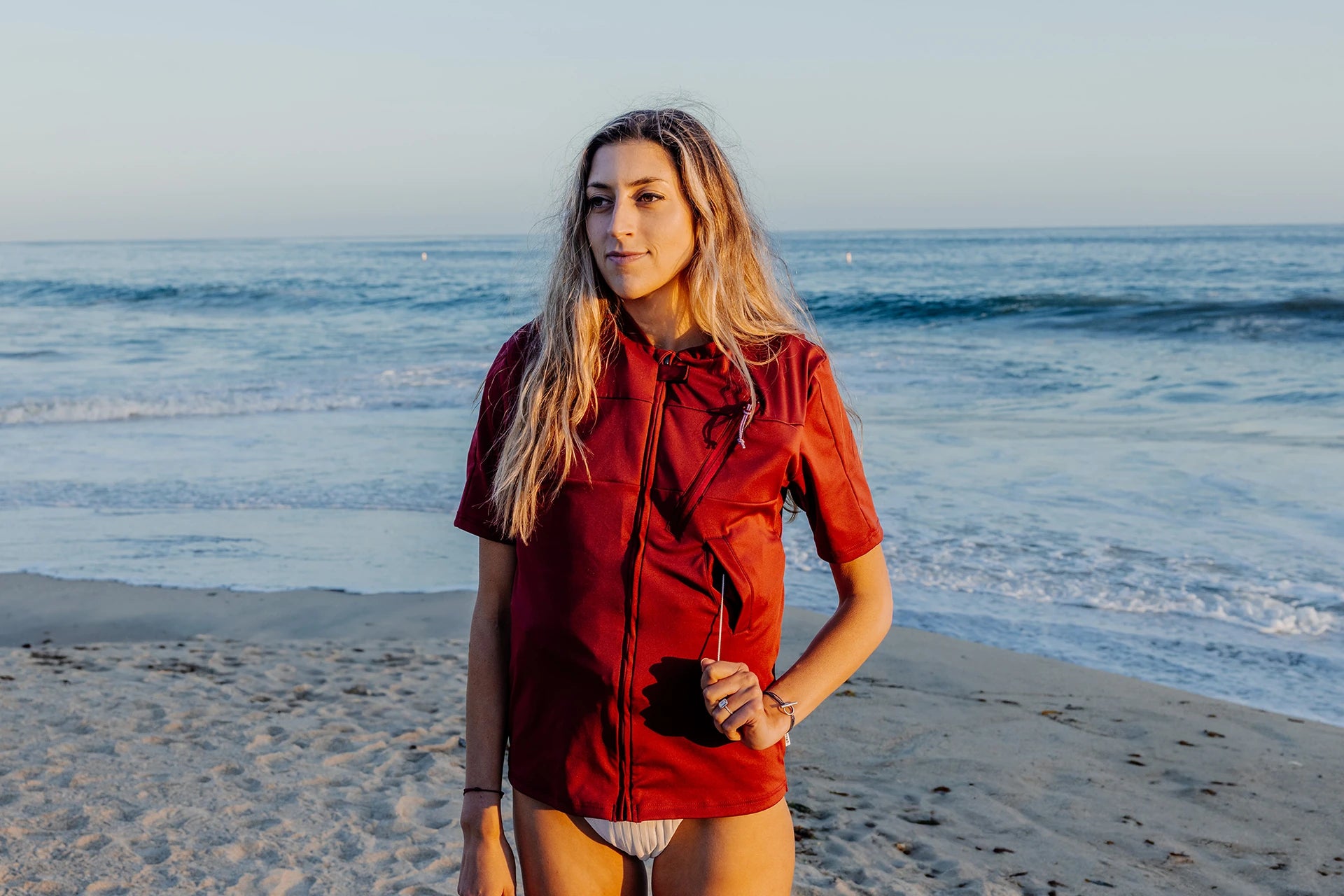 Femme sur une plage et portant le tee-shirt anti-noyade adulte manuel Floatee, tirant la languette, manches courtes, rouge