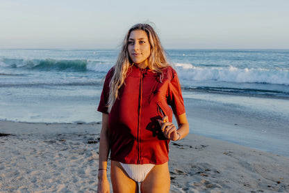 Femme sur une plage et portant le tee-shirt anti-noyade adulte manuel Floatee gonflé, manches courtes, rouge