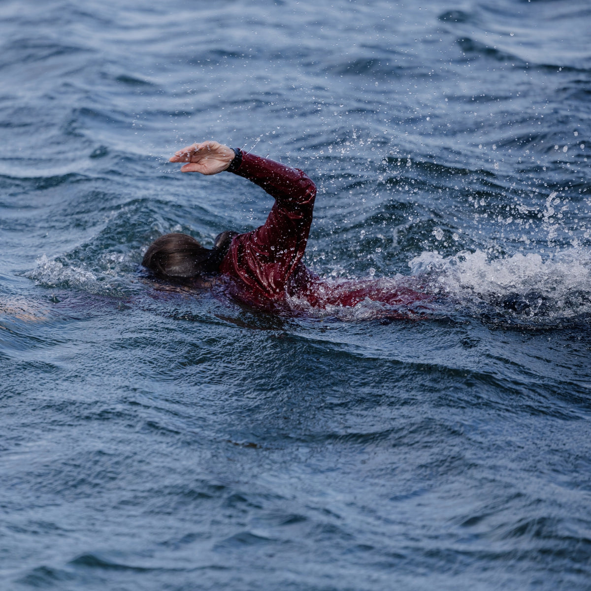 femme nageant en mer et portant un T-shirt anti-noyade Floatee rouge à manches longues
