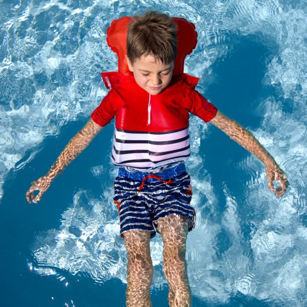 Enfant dans piscine, portant le tee-shirt anti-noyade Floatee (rouge, manches courtes) qui s'est gonflé pour sauver l'enfant de la noyade