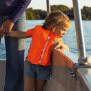 Une petite fille sur un bateau portant un gilet de sauvetage Floatee A100 et regardant l'eau